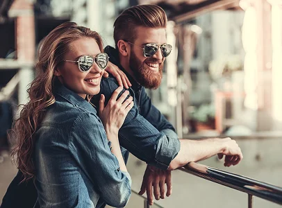 Couple souriant en denim et lunettes de soleil, s'appuyant sur une rampe, heureux à Montigny-le-Bretonneux dans les Yvelines 78
