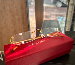 Lunettes Cartier dorées sans monture posées sur un étui rouge avec logo à Montigny-le-Bretonneux dans les Yvelines 78