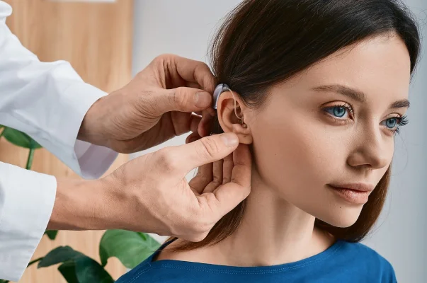 Un médecin ajuste un appareil auditif derrière l'oreille d'une jeune femme à Montigny-le-Bretonneux dans les Yvelines 78