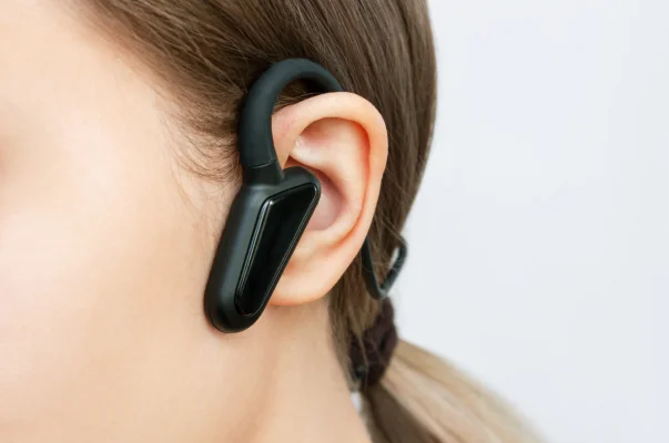 Oreille avec écouteur noir à conduction osseuse, cheveux tirés en arrière à Montigny-le-Bretonneux dans les Yvelines 78